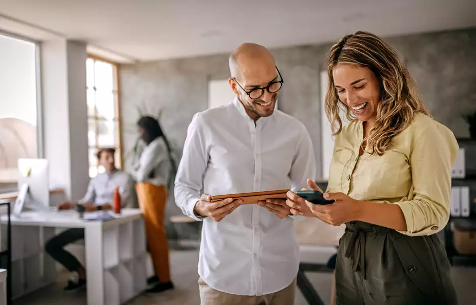 Un homme et une femme dans un bureau qui regardent une tablette